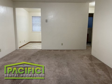 the living room and dining room of a new home with carpeting and a door