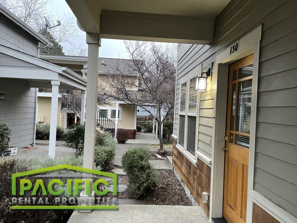 a walkway between two houses with a wooden door and a porch