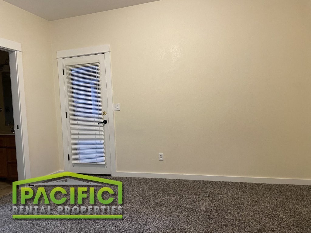 a room with a carpet and a door and a pacific rental properties logo