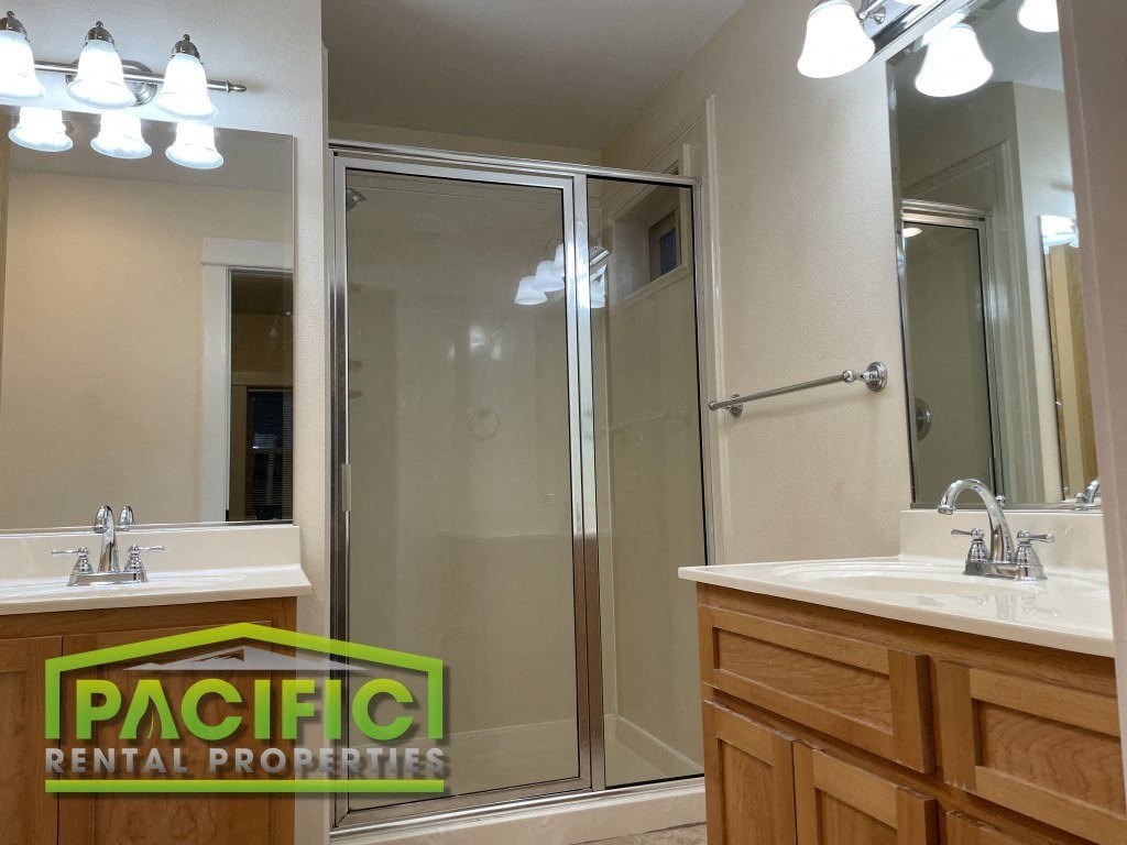 a bathroom with a shower and sink and a pacific rental properties logo