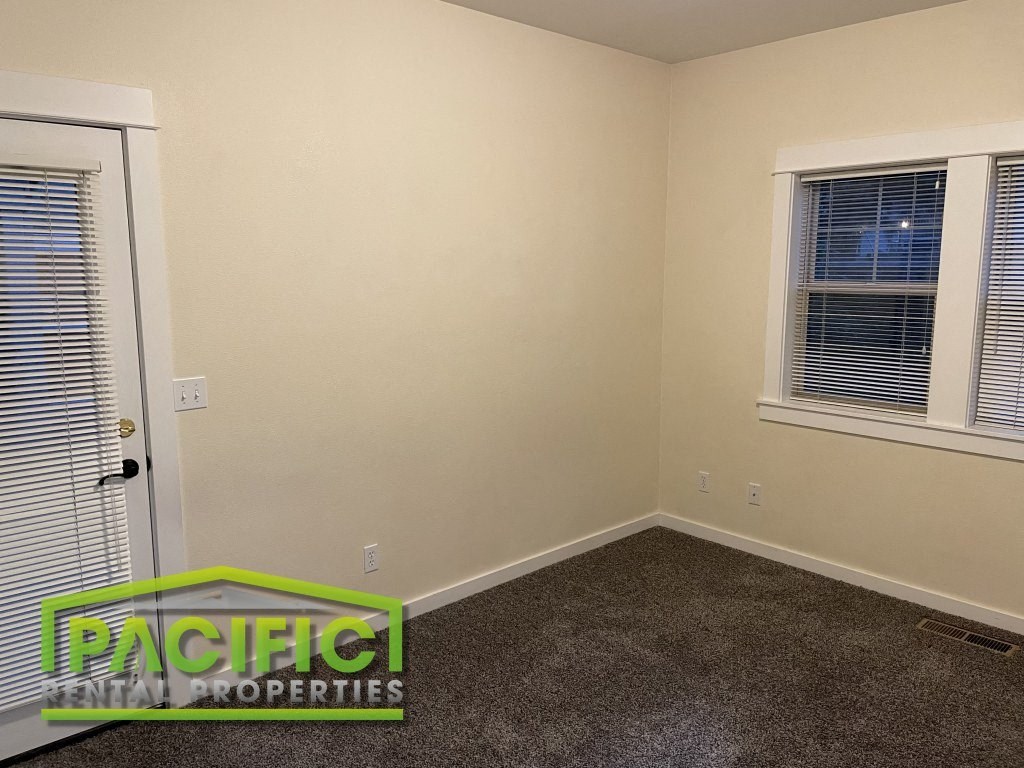 a room with a carpeted floor and two windows