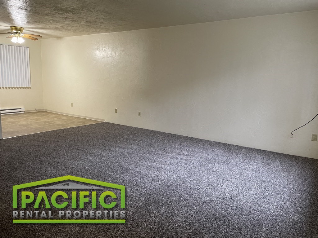 an empty room with a carpeted floor and a pacific rental properties logo