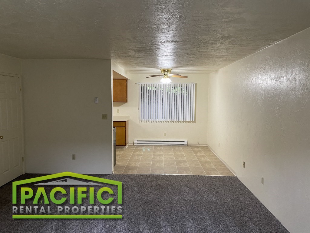 the living room and dining room of an empty house with a ceiling fan