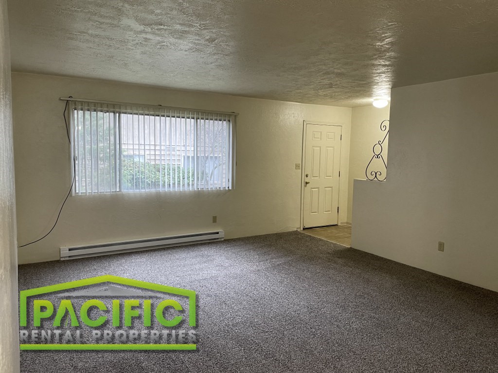 the living room of an empty house with carpet and a window