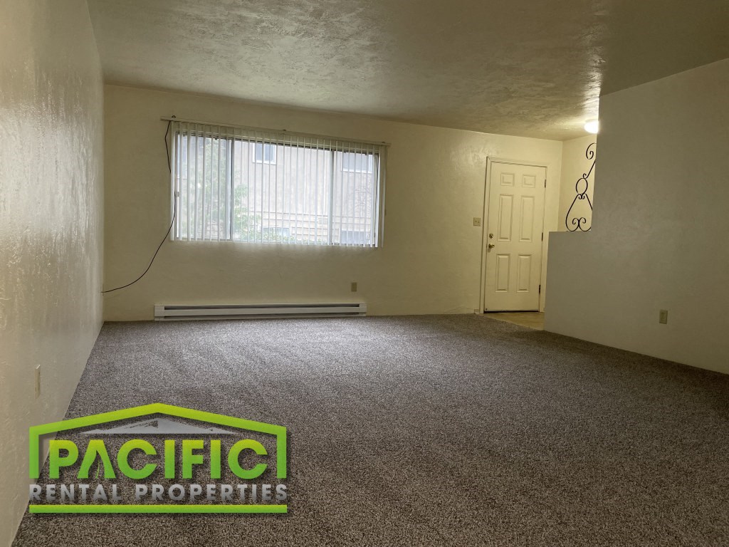 the living room of a house with carpet and a window