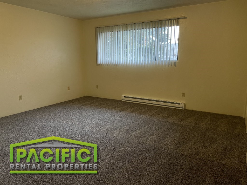 the interior of an empty room with carpet and a window