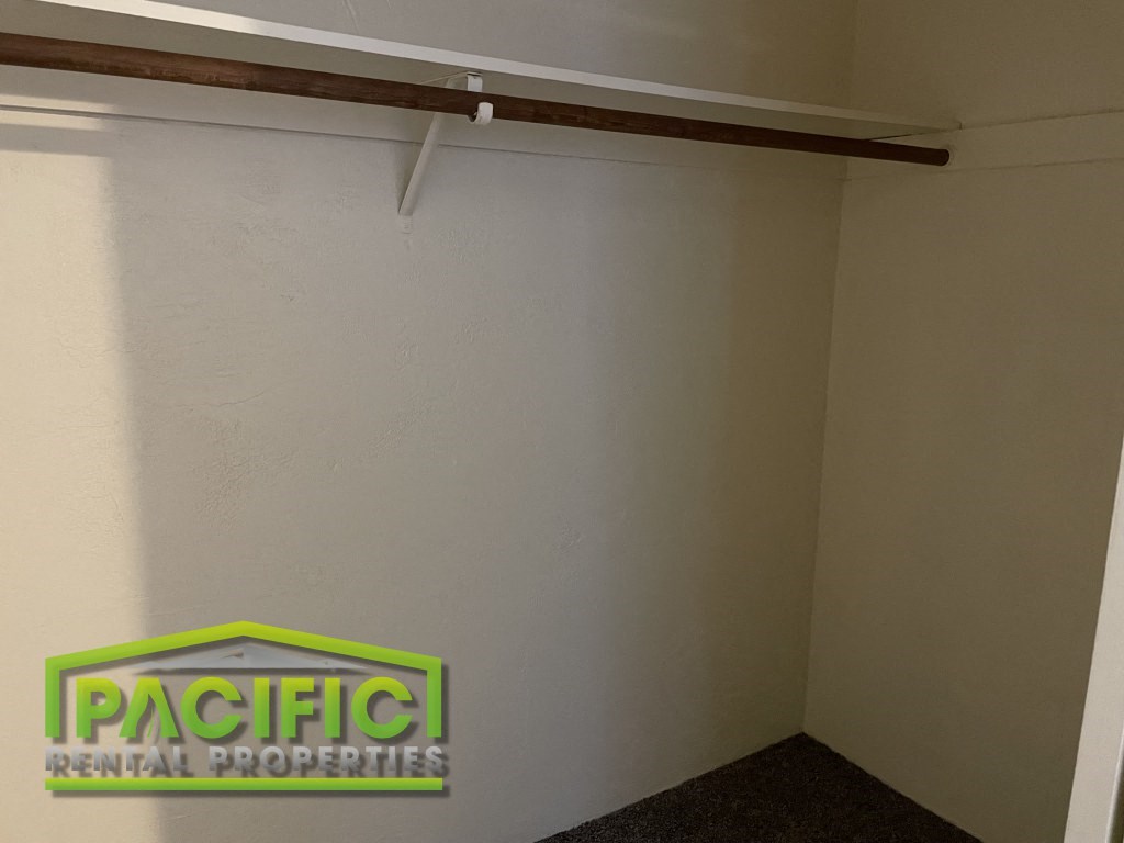 a closet with a white wall and a wooden ceiling beam