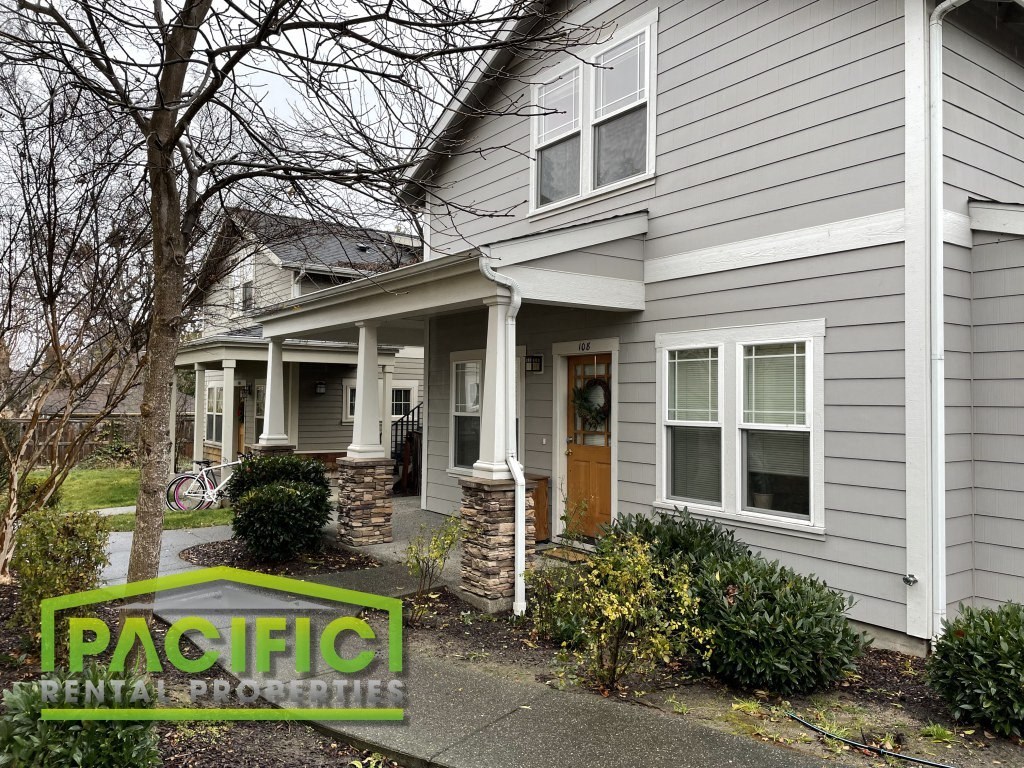 a white house with a front porch and a sign on the sidewalk