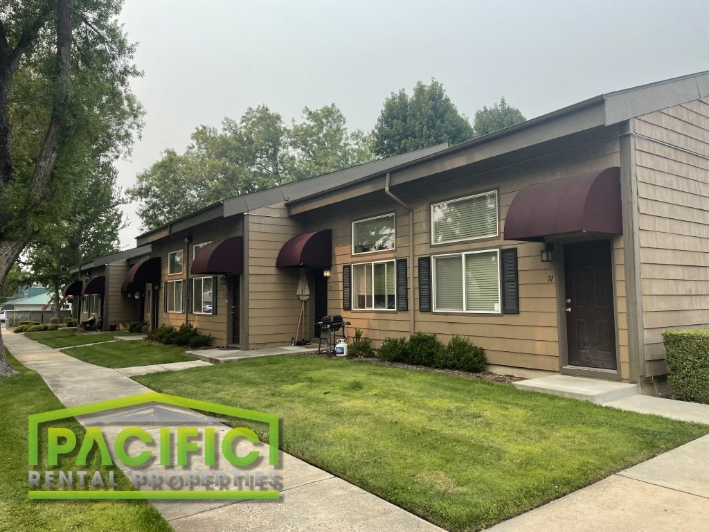 a row of houses with brown siding and green grass
