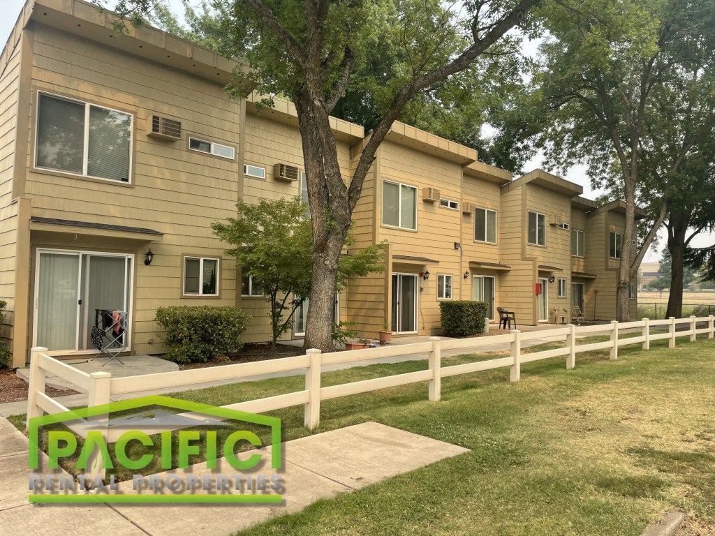a yellow apartment building with a white fence