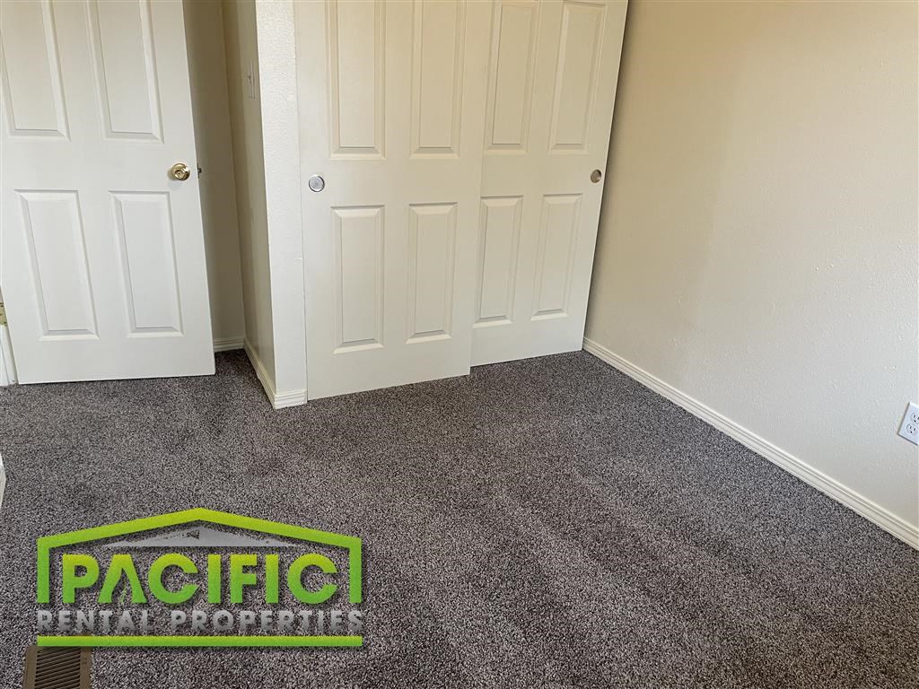 a carpeted room with a door and a pacitech logo on the floor