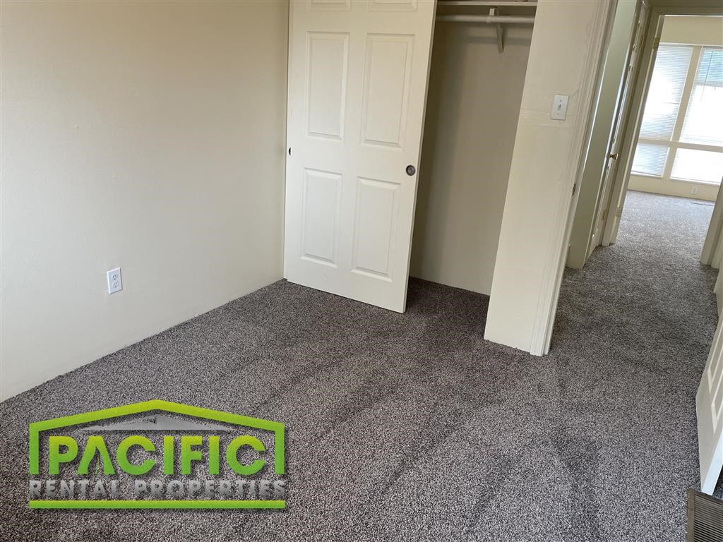 a carpeted room with a door and a pacific logo on the floor