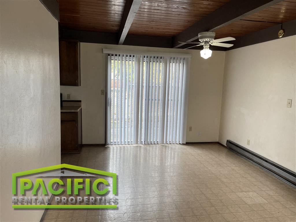 an empty living room with a ceiling fan and a window