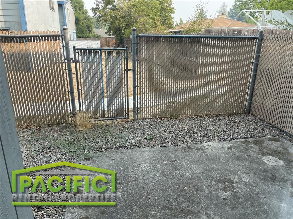 a fence with a gate and a yard with gravel