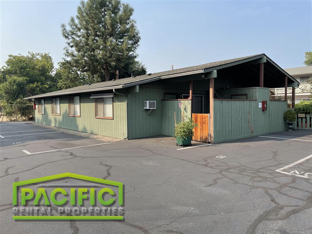 a green building with a parking lot and a tree