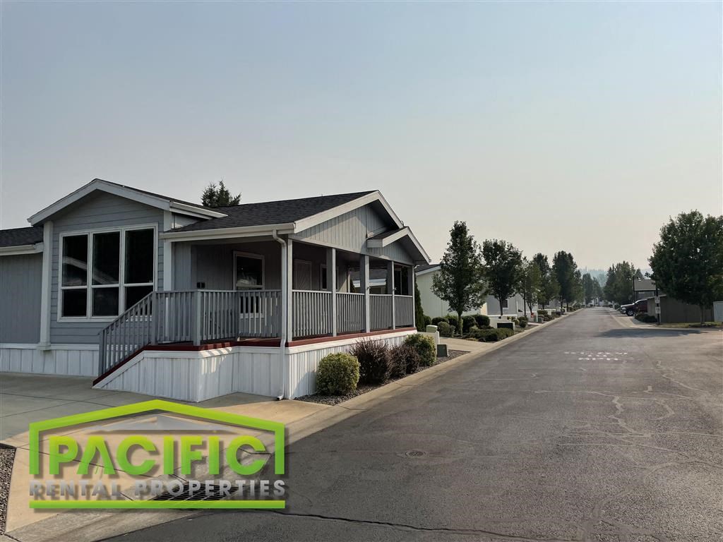 a white house with a porch on the side of a street
