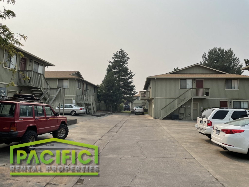 an empty parking lot with cars in front of apartment buildings