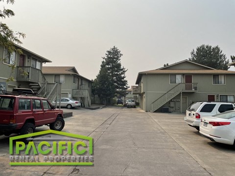 an empty parking lot with cars in front of apartment buildings