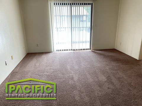 a carpeted room with a window and a pacific logo on the floor