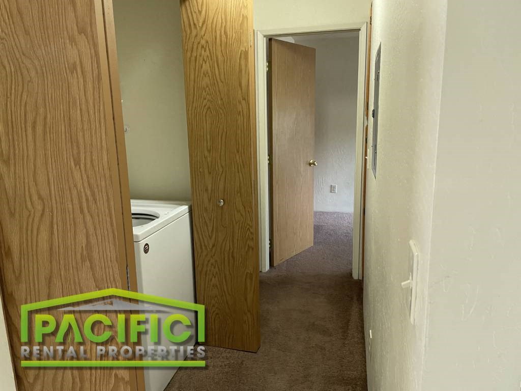a hallway with a laundry room and a door to a closet