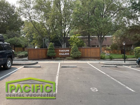an empty parking lot with a parking lot sign in front of a building