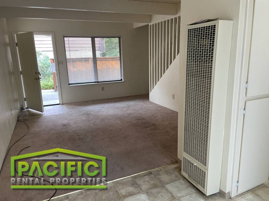 an empty living room with a heater and a staircase