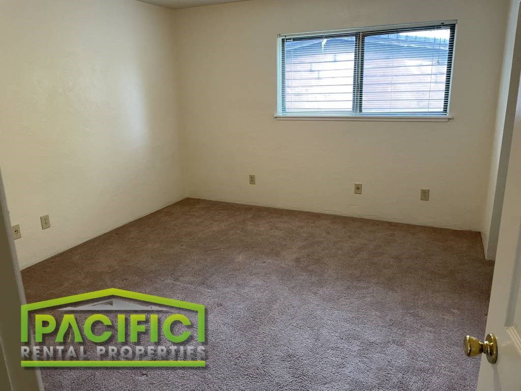 an empty room with a window and a carpeted floor