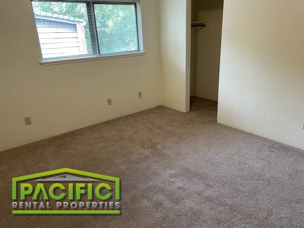 a carpeted room with a window and a pacificentalental properties logo