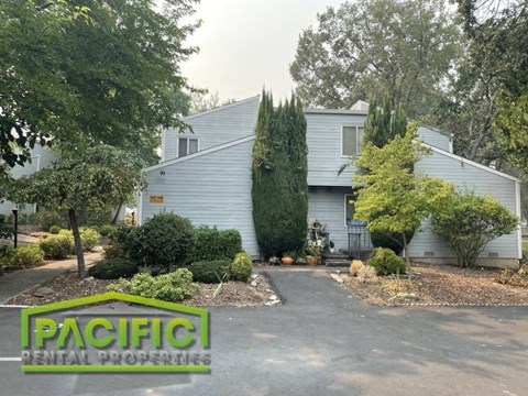 a white house with a driveway and trees