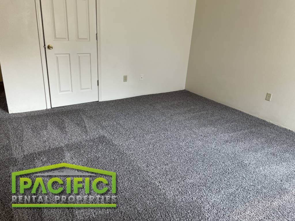 a carpeted room with a door and pacific logo on the floor