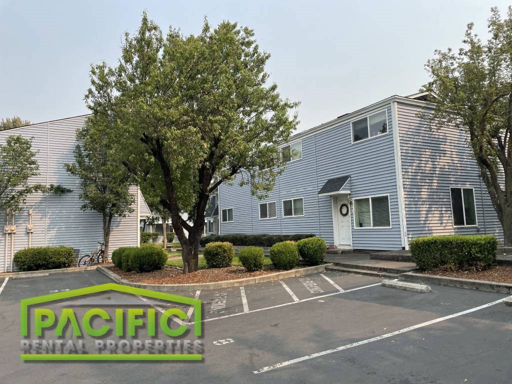 a blue building with a tree in front of it in a parking lot