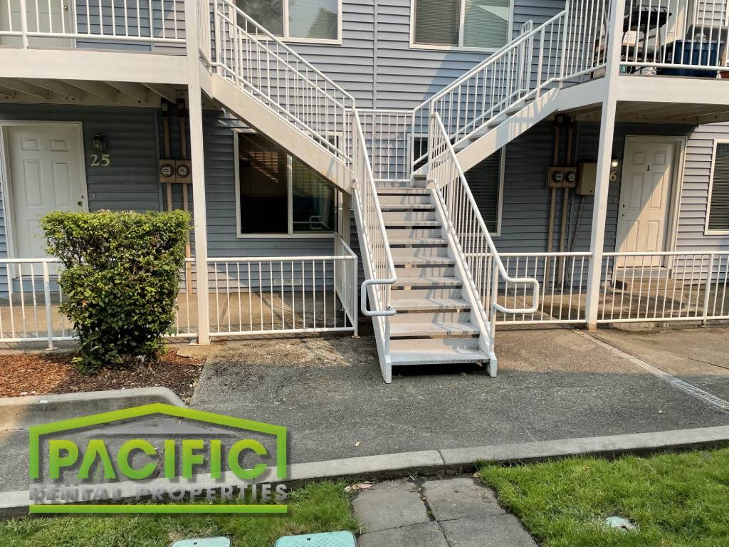 an apartment building with stairs and a sidewalk