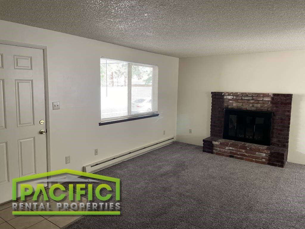 an empty living room with a brick fireplace