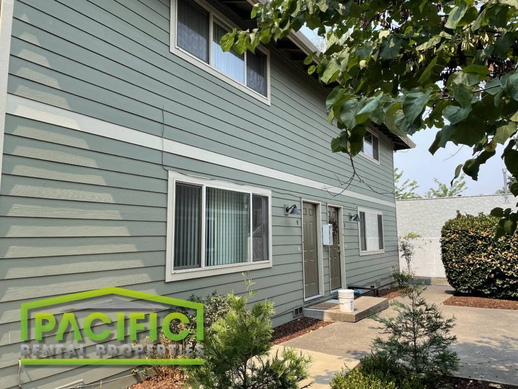 a side view of a green house with a sidewalk