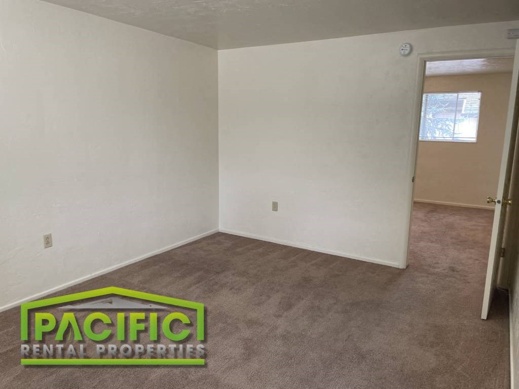 an empty living room with a carpeted floor and a window