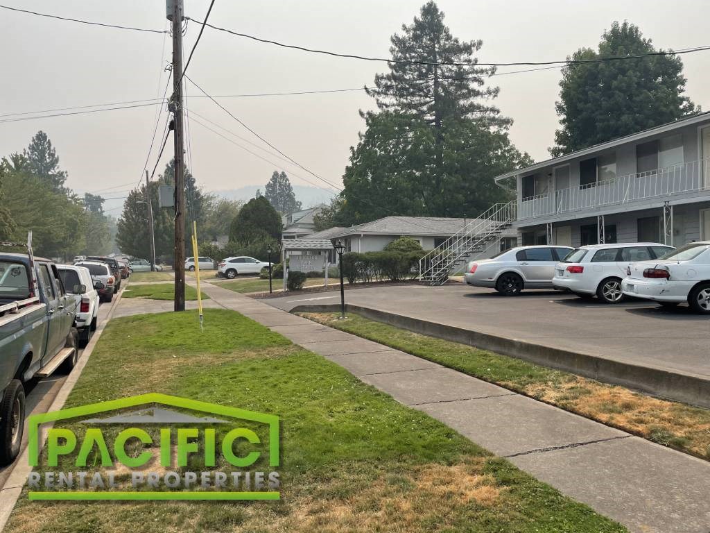 a group of cars parked in a parking lot next to a sidewalk