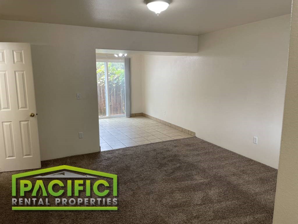 an empty living room with carpet and a door to a patio