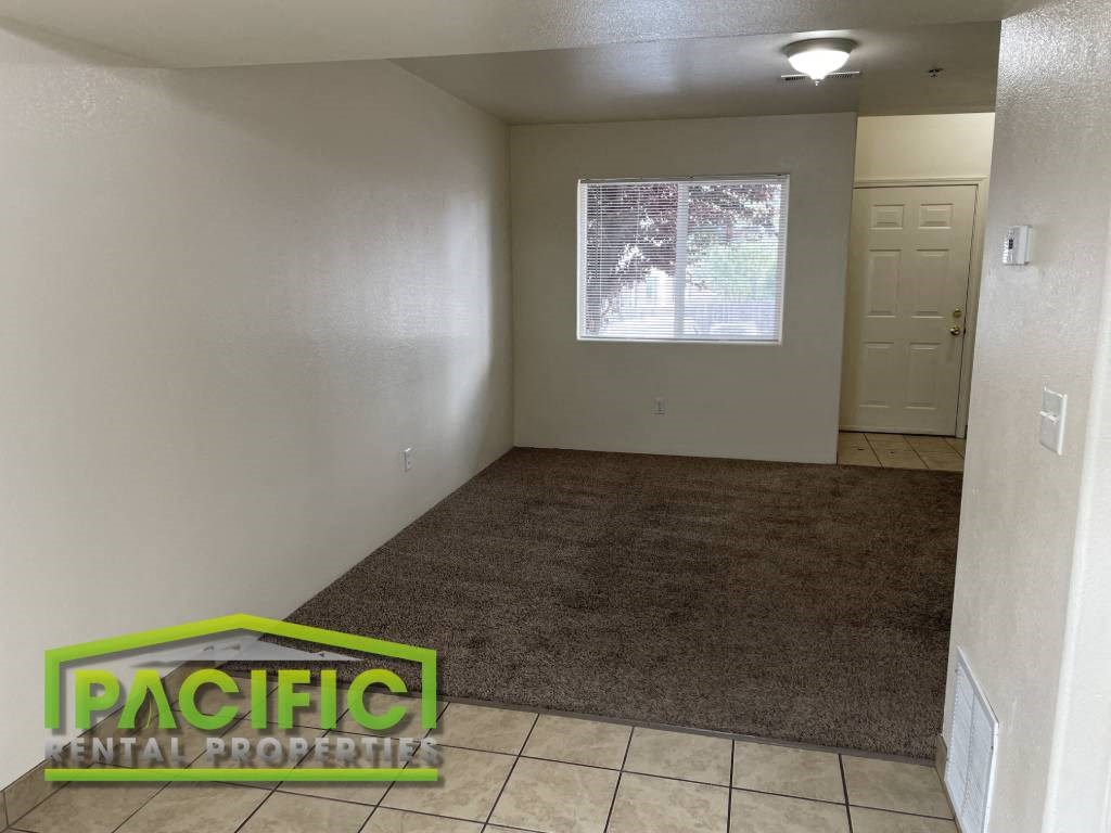 an empty living room with a carpet and a window
