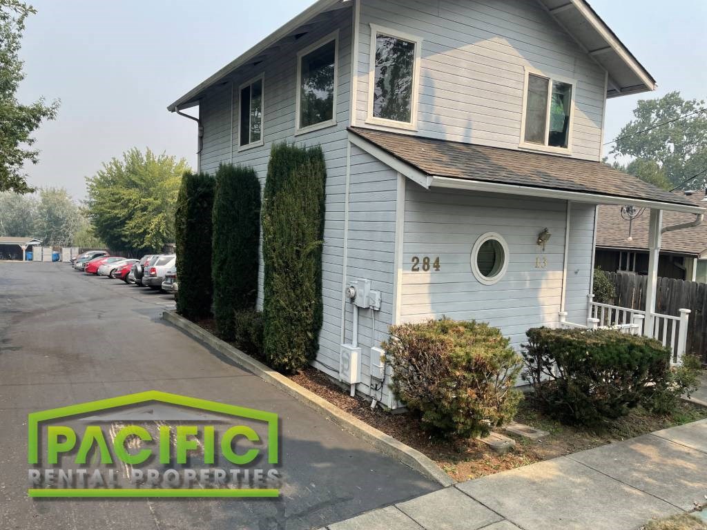 a small white house with a parking lot