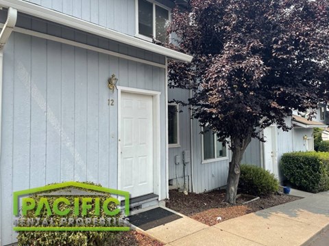 a blue house with a white door and a tree