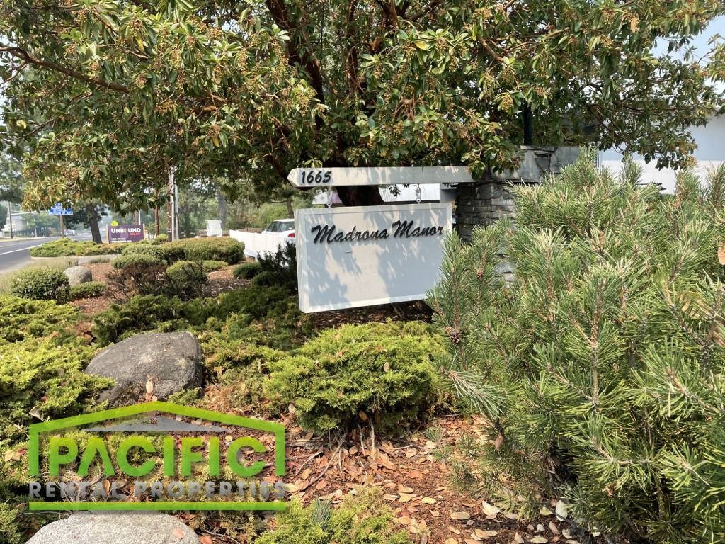 a sign in a garden with bushes and trees