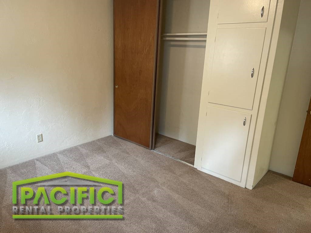 a carpeted room with a closet and a pacific rental footprints logo