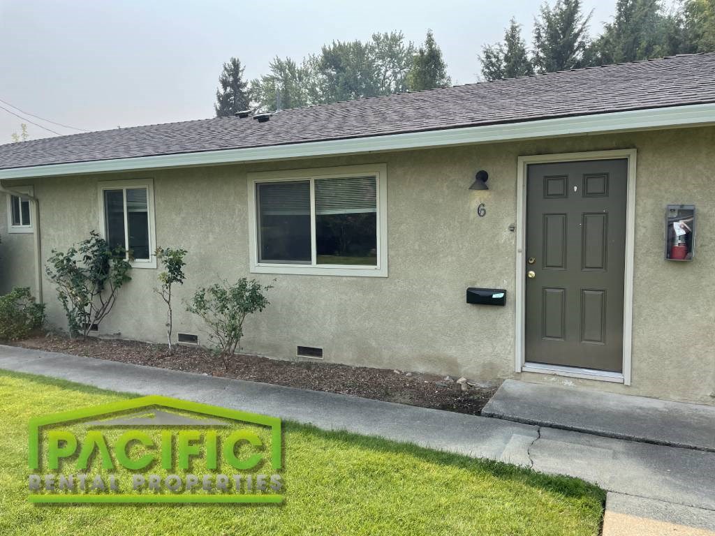 a tan house with a brown door and a lawn