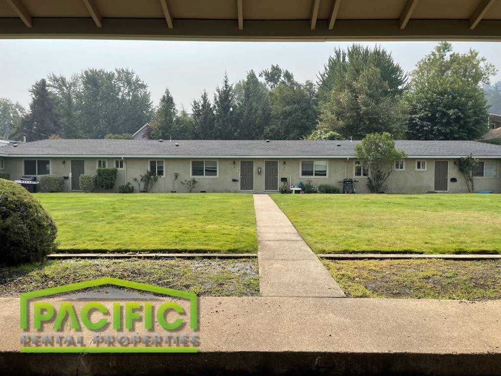 a house with a lawn and trees in the background