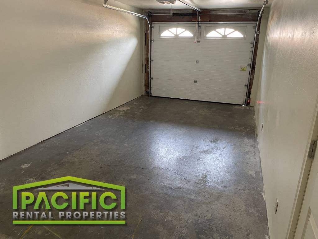 A spacious garage with two doors and a logo for Pacific Rental Properties.