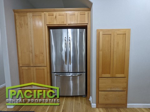 a stainless steel refrigerator in a kitchen with wooden cabinets