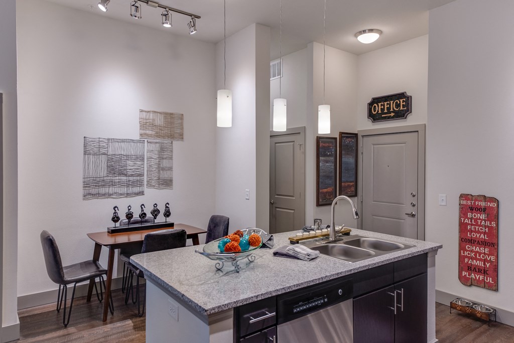 a kitchen counter with a sink and a dining room with a table and chairs