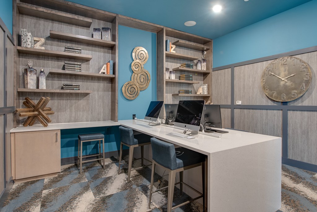 a home office with a large clock on the wall and a desk with two computers