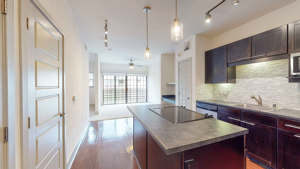 a kitchen with an island and a door to a living room