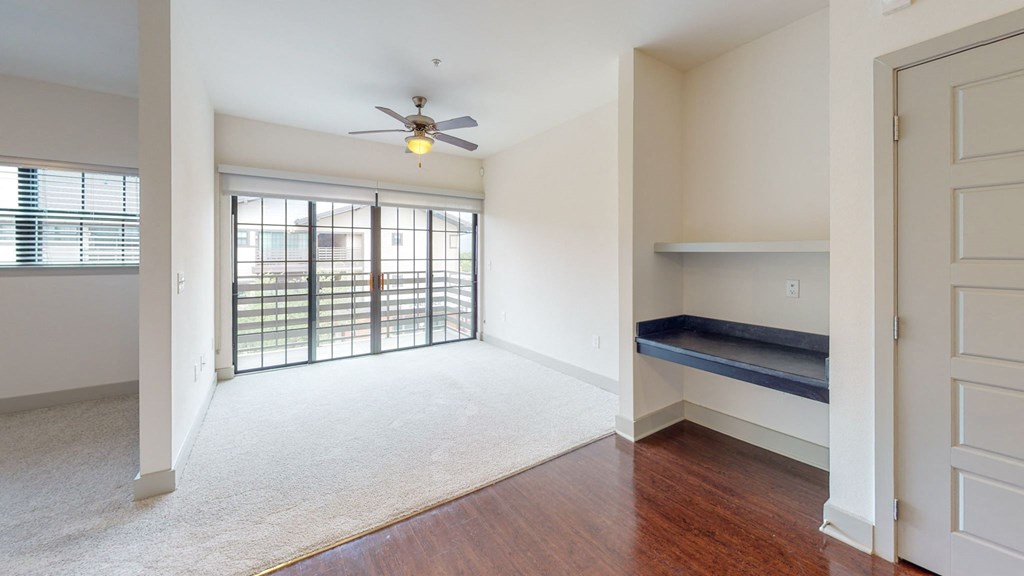 an empty living room with a ceiling fan and a window